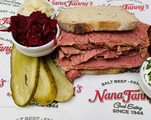 Load image into Gallery viewer, This is our Salt Beef reheated, sliced and served in a classic rye bread. We've added pickled gherkins and latkes